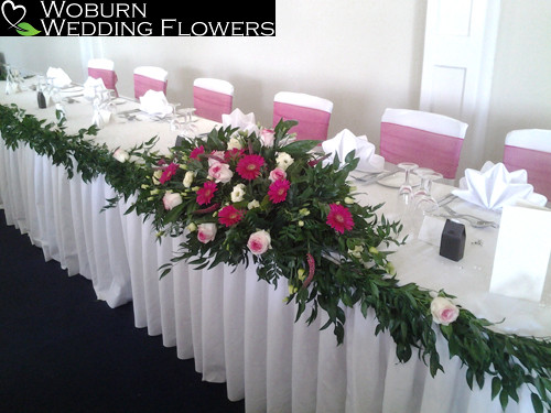 Top table arrangement with Gerbera, Rose and Freesia with a Rose decorated garland.