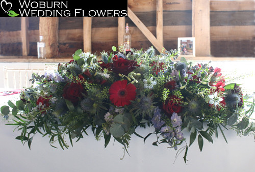 Ceremony flowers in reds and blues including Gerbera and Nigella.